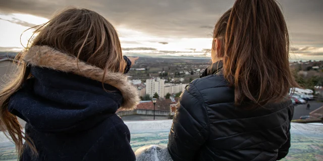 Deux filles de dos regardent un panorama sur les hauteurs de Thiers, mêlant ville et nature.