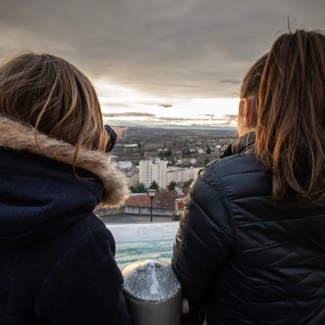 Deux filles de dos regardent un panorama sur les hauteurs de Thiers, mêlant ville et nature.