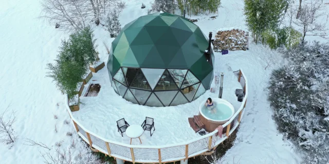 Vue aérienne de l’éco-lodge des Bois de Luna, entouré de neige, dans un paysage naturel et apaisant.