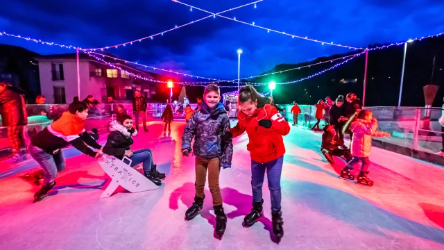 Des enfants profitent de la patinoire illuminée au Marché de Noël de Thiers, entourés de décorations lumineuses, dans une atmosphère festive et familiale