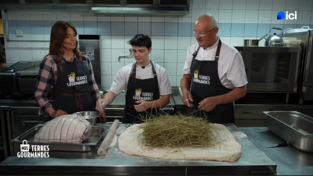 Carinne Teyssandier, un chef et un apprenti devant des ingrédients dans une cuisine, portant des tabliers, scène de l’émission culinaire Nos terres gourmandes sur France 3.